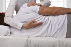 chiropractor adjusting male patients upper back 