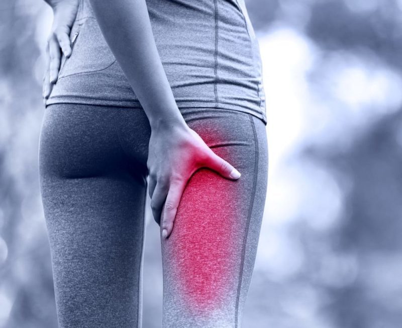 woman holding her upper leg due to sciatic nerve pain