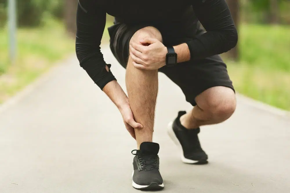 Young male runner is suffering from ankle
