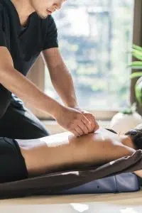 Therapist Giving acupuncture Treatment To Young Woman
