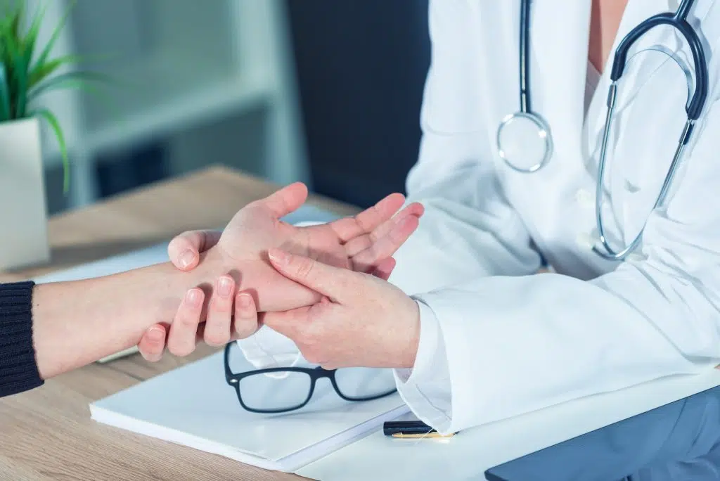 female patient having her hand examined by a doctor 