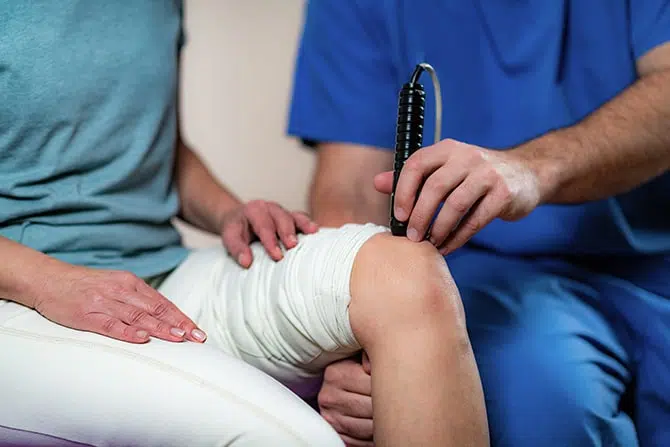 Chiropractor doing the Laser therapy to the patient