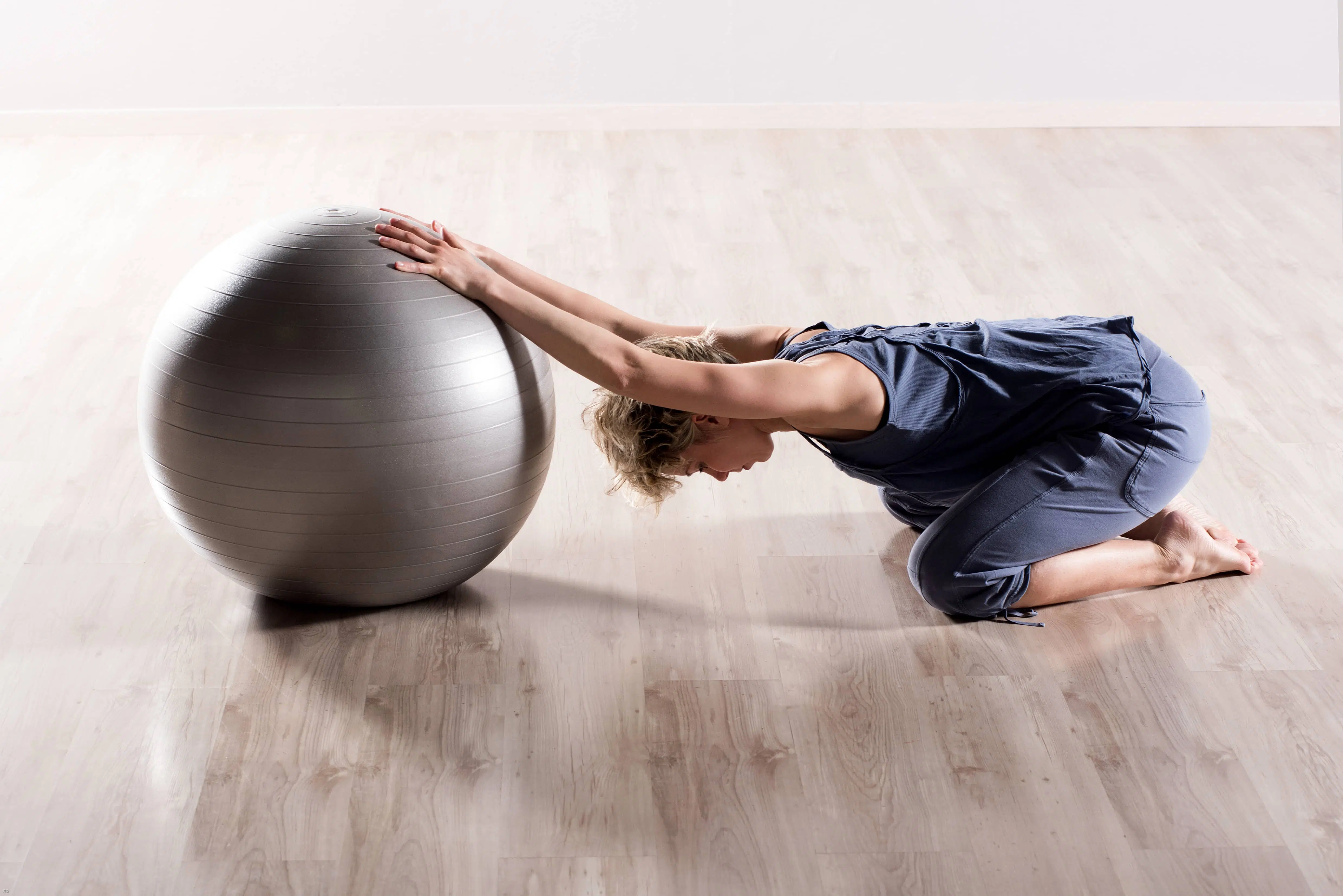 woman stretching using exercise ball as corrective exercises