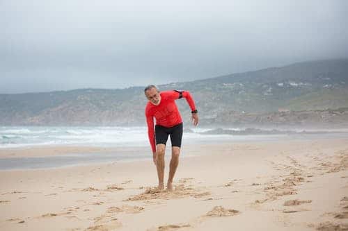 old man having leg pain on the beach