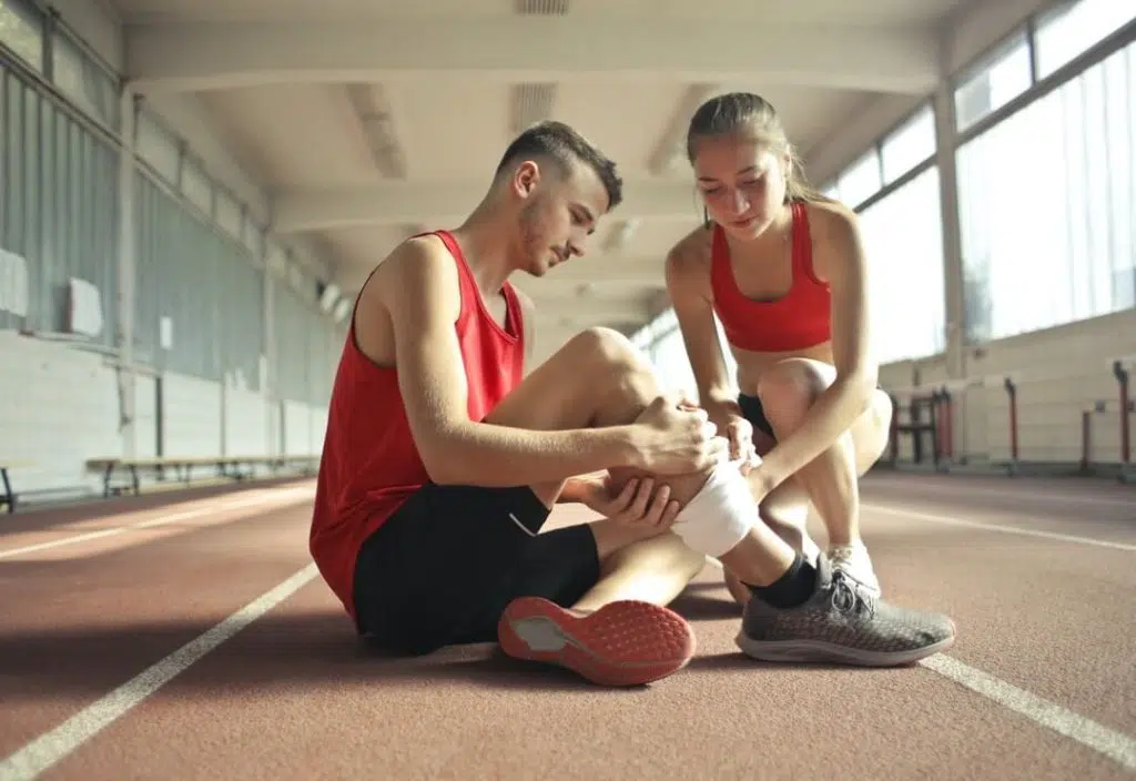 Woman wrapping man's leg with bandage due to leg pain