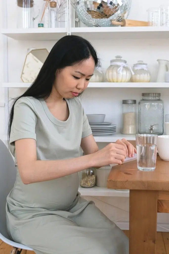 Pregnant woman preparing to drink a medicine