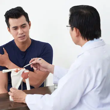 male patient talking with doctor about his shoulder pain | chiropractic techniques for auto accident recovery