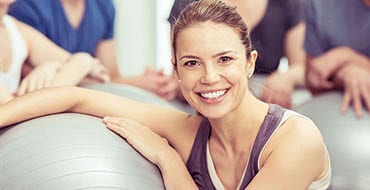 smiling woman next to a gym ball