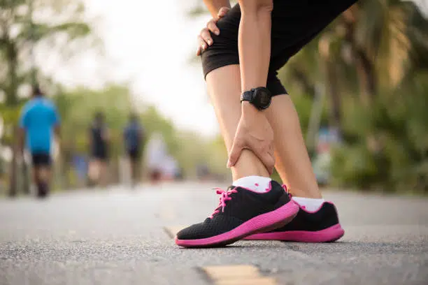 Woman suffering from an ankle injury while exercising. Running sport injury concept.