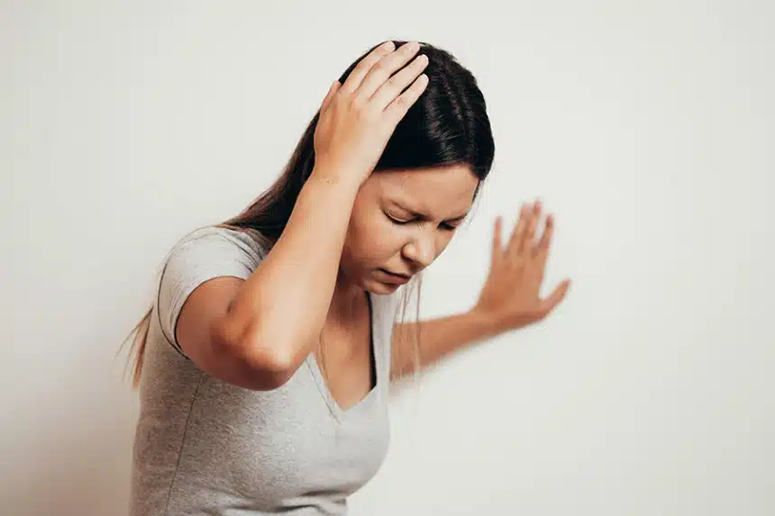 Dizzy woman suffering vertigo attack standing in the living room at home