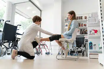 Orthopedist woman putting a knee brace on a young female client