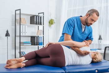 chiropractor-massaging-back-of-patient that lying on massage table in hospital
