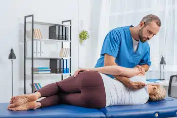 chiropractor massaging back of patient that lying on massage table in hospital