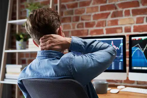 man with whiplash holding his neck from pain while working