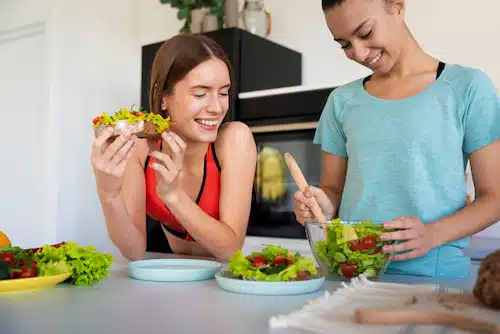 two women preparing a healthy bowl of vegetable salad | chiropractic care for head injuries